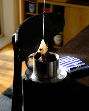 Lifting a steeped coffee bag from the cup