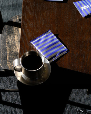A finished cup of Citrus Bloom beside its steeped bag